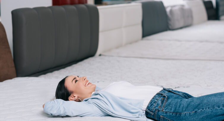 side view of smiling customer lying on orthopedic mattress in furniture store